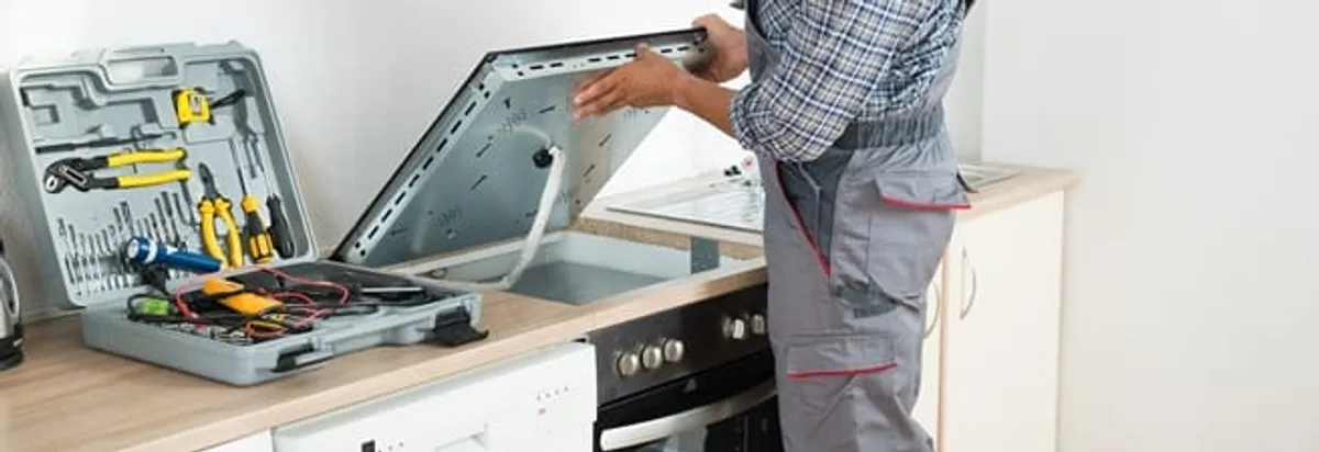 Cooktop repair technician lifting a built-in stovetop for service in Scottsdale, AZ