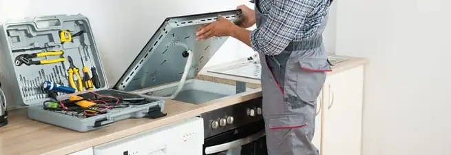 Cooktop repair technician lifting a built-in stovetop for service in Scottsdale, AZ