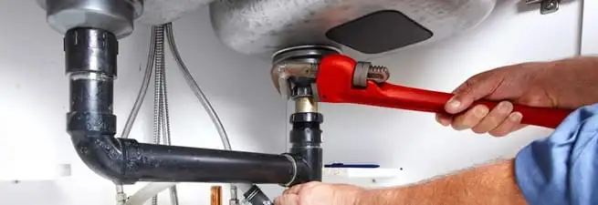 Garbage disposal repair technician tightening the sink drain and disposal connection in Scottsdale, AZ
