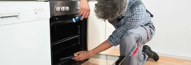 Oven repair technician inspecting and servicing an electric oven in Scottsdale, AZ