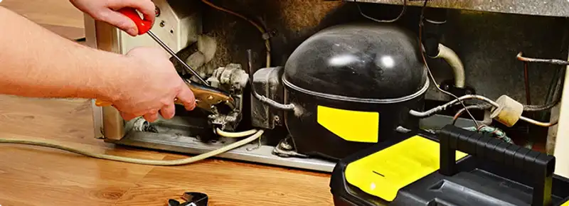 Refrigerator repair technician fixing the compressor and wiring in Scottsdale, AZ